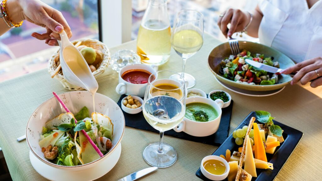 An elegant dining setup with fresh salads, wine, and assorted sauces in a modern setting.